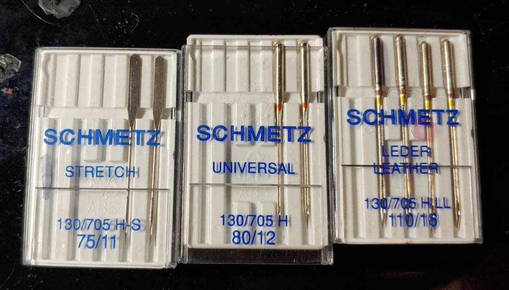 Several sewing machine needles. From left to right: stretch, universal, leather