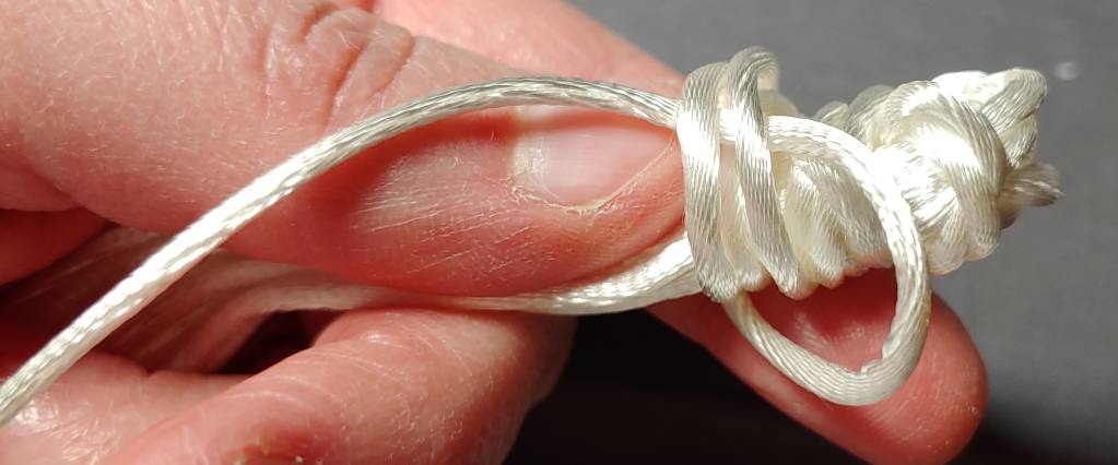 Finishing off the knot by slipping the tail into the loops wound around the tassel