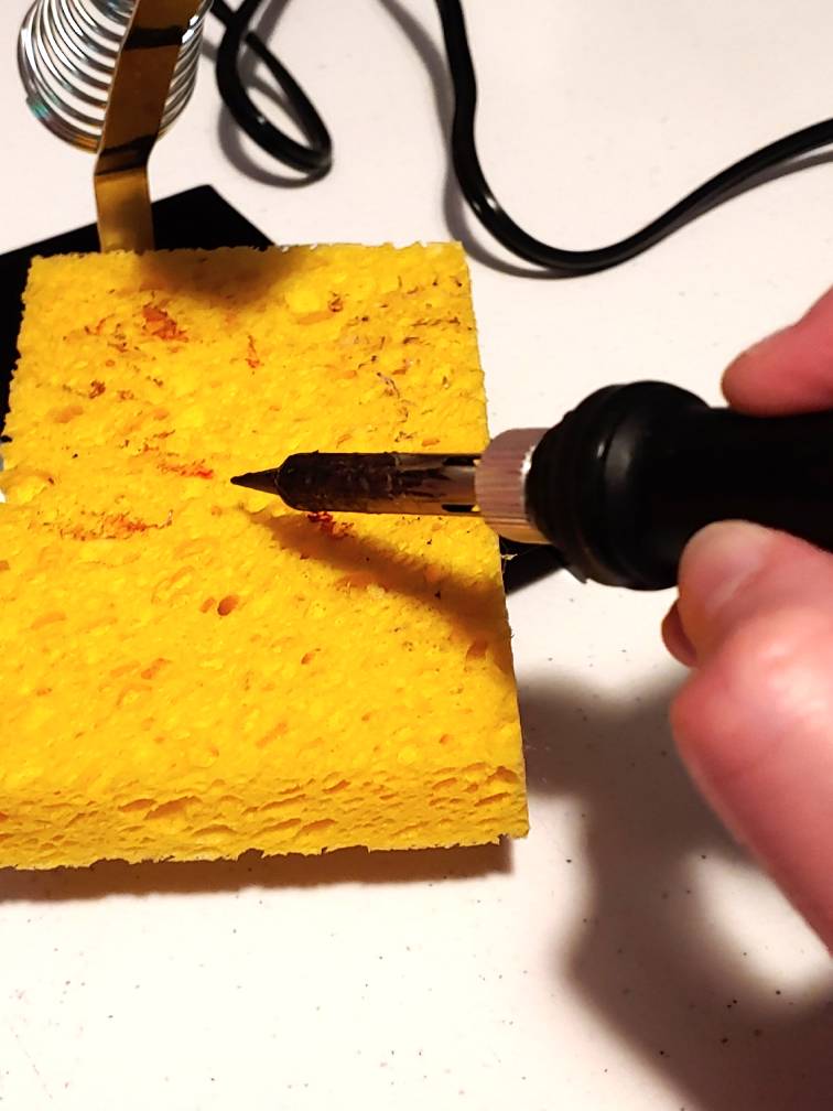 Cleaning the iron tip involves rolling the tip across the sponge