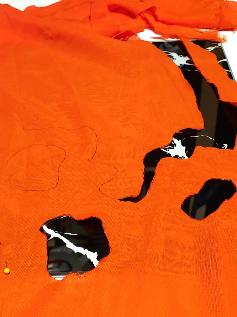 Chiffon partially cut, showing squiggle patterns and cutouts that resemble a distressed flame design