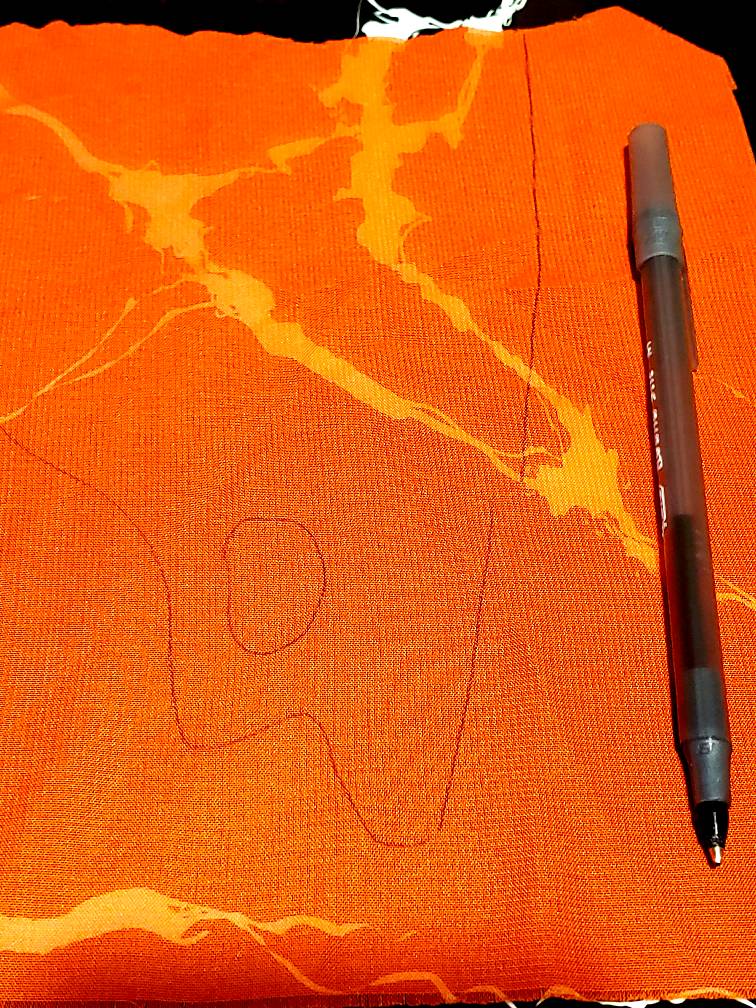 A test piece of chiffon fabric with a flame pattern drawn out in pen.