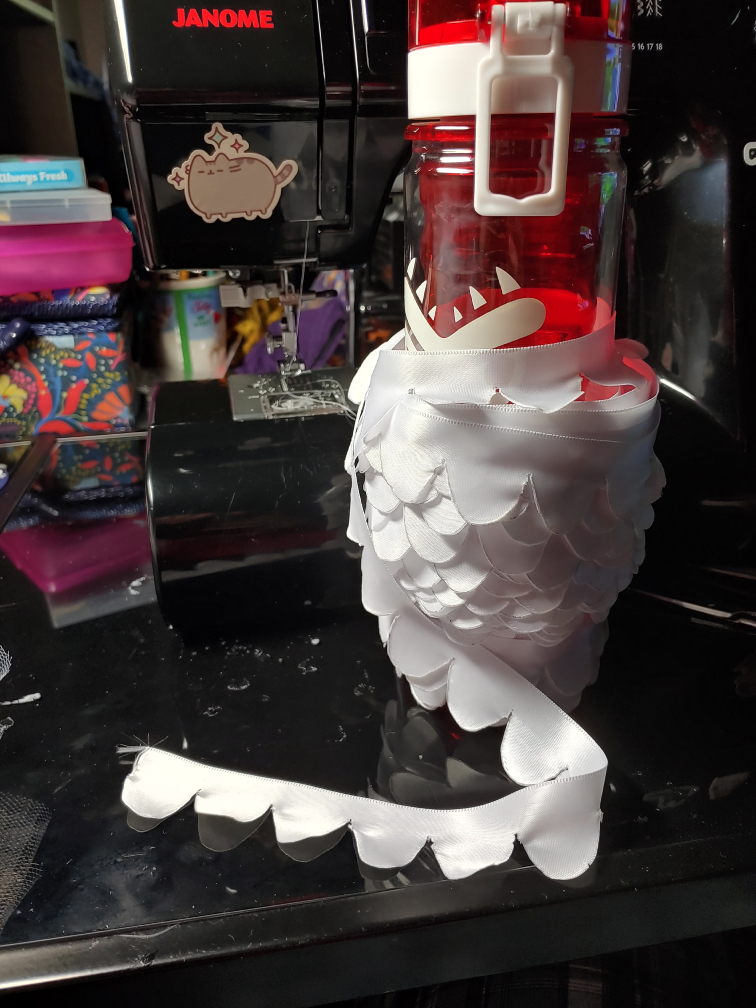 Cut scalloped ribbon wound around a water bottle to make a temporary spool