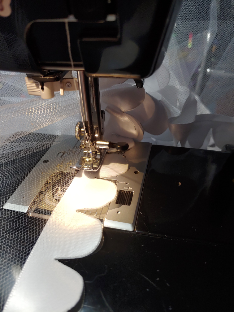 Trim being sewn down to the bottom tier, a bunch of sewn tulle piling up behind the sewing machine.