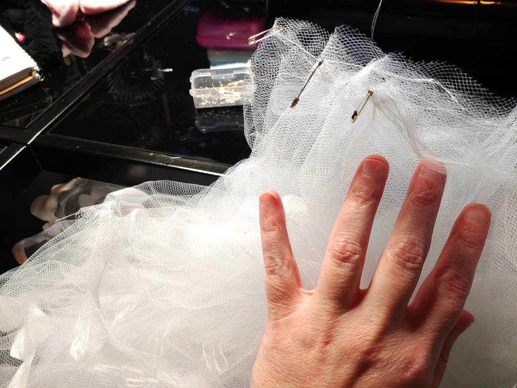 Pinning the petticoat tier once again. Half the petticoat is stuffed under the desk.