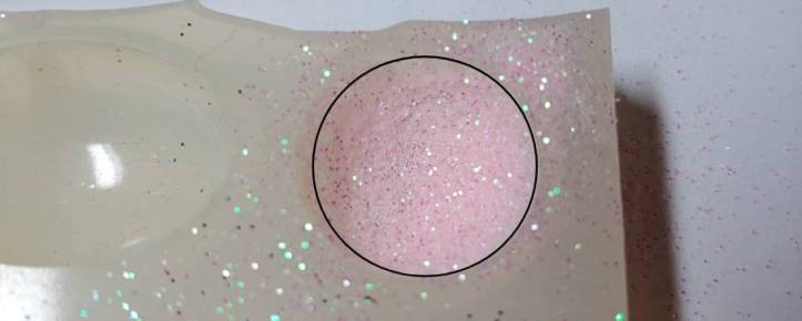 Glitter spread evenly around the mold. Edges of the mold marked in black
