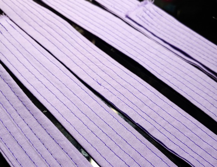 A pile of straps with stitched lines in a contrasting purple