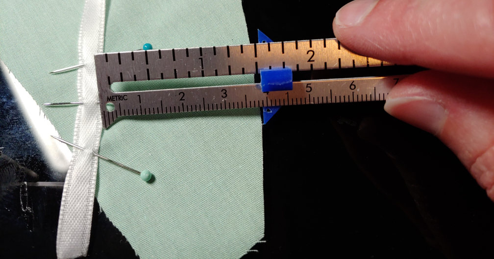 A sewing gauge used to measure the distance between the edge of the fabric and the ribbon