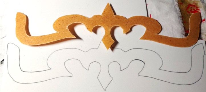 The Worbla crown sitting on white foam, the shape traced in pen