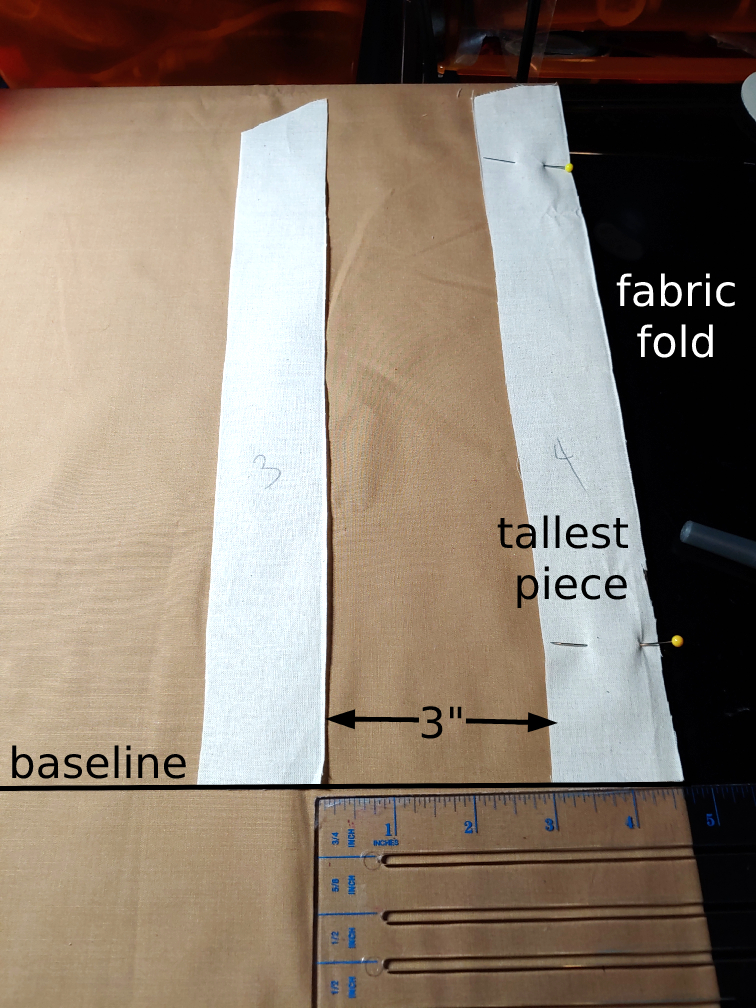 How to start placing the strips of fabric on the folded scrap fabric. The tallest piece is placed flush against the fabric fold with the next piece in size placed 3" away.