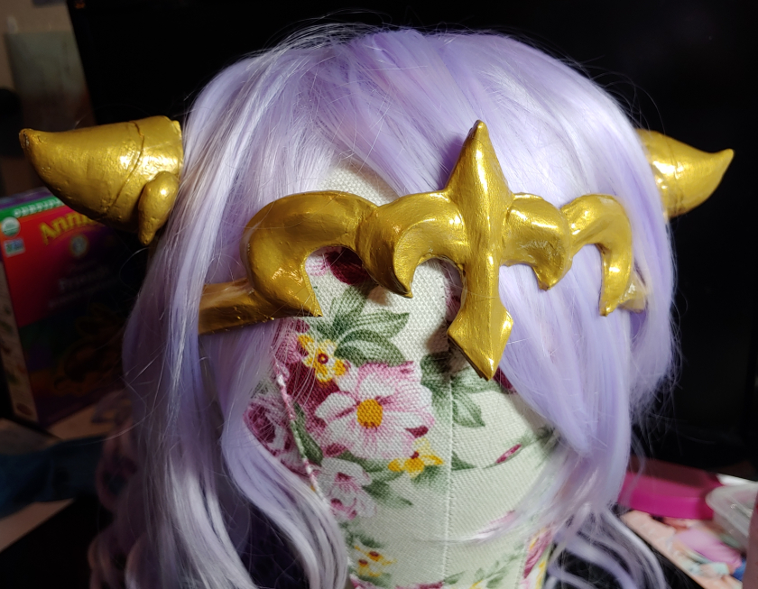 Finished gold Camilla crown tucked into a lavender wig on a wig head
