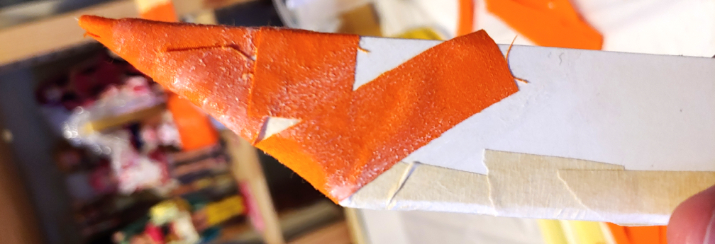 progressively longer strips of orange fabric wrapped around the tip of a katana