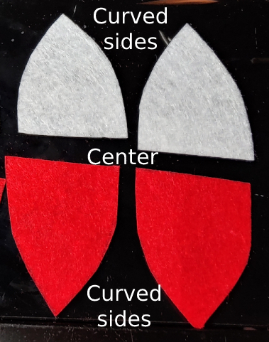 Two pieces in red and two in white showing the pieces of each Pokeball pattern piece. The small flat side forms the center while the curved sides form the curved side of the Pokeball