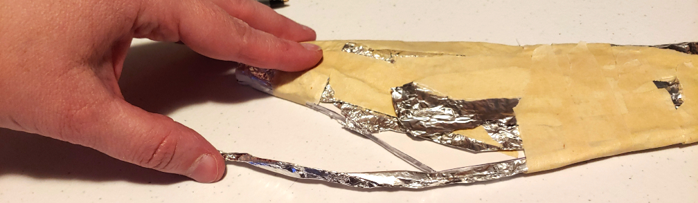 Adding a thin rolled noodle of foil to cover the edge of the foam core board. The noodle is then wrapped with tape to hold it in place.
