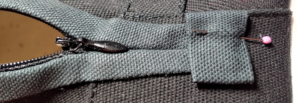 Little zipper cap, pinned in place at the bottom of the zipper and expansion sections. The zipper is mostly unzipped to make it easier to reach the cap.