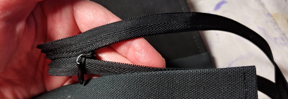 Checking the direction and placement of the zipper. The zipper teeth are hidden and the zipper pull is facing forward.