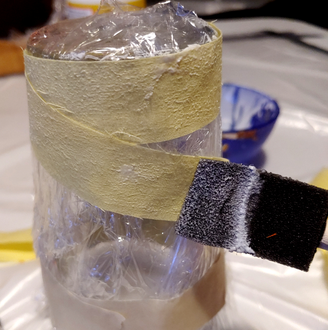 Decoupaging strips around the glass. The glue is still wet as the sponge brush applies Mod Podge to make it stick to itself.