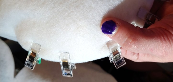 Felt held along the side of the foam using clear fabric clips. the felt is nice and smooth with no wrinkles.