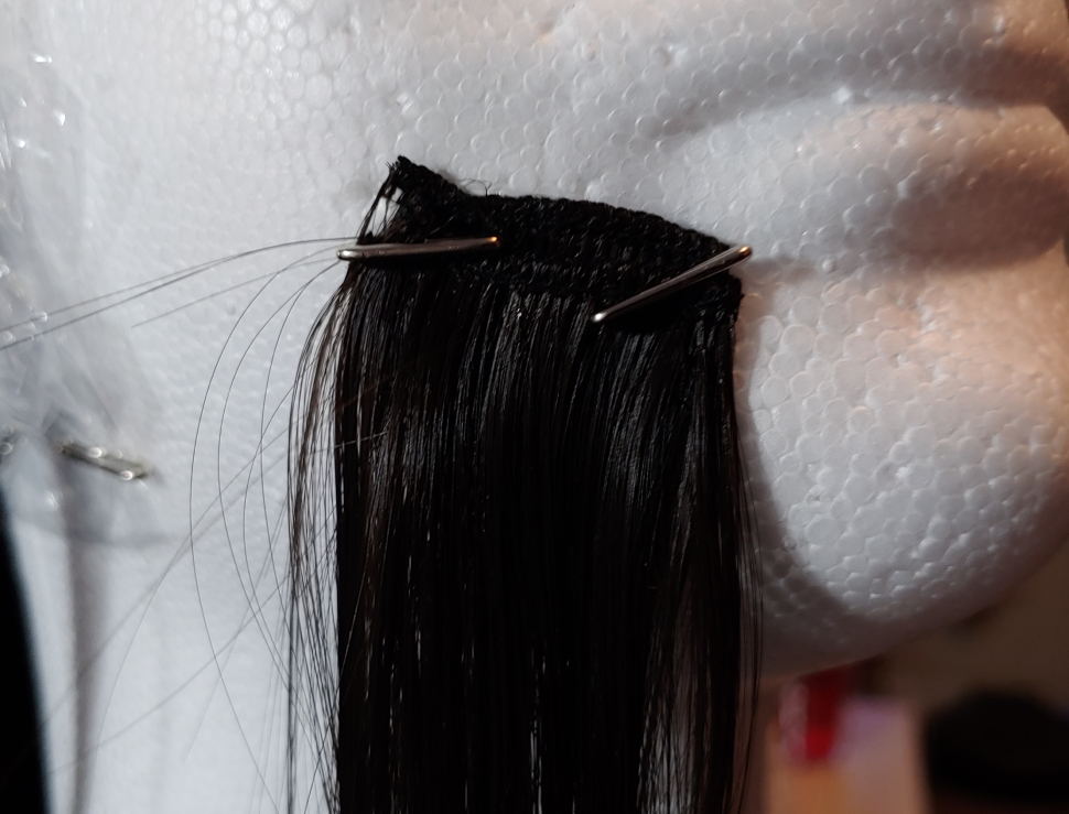 Fibers pinned to the wig head using large wig pins.
