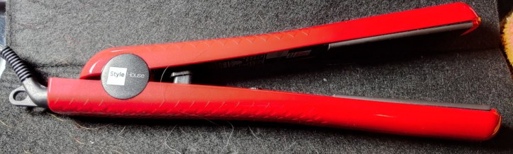 A simple red flat iron sitting on a heat-resistant pad