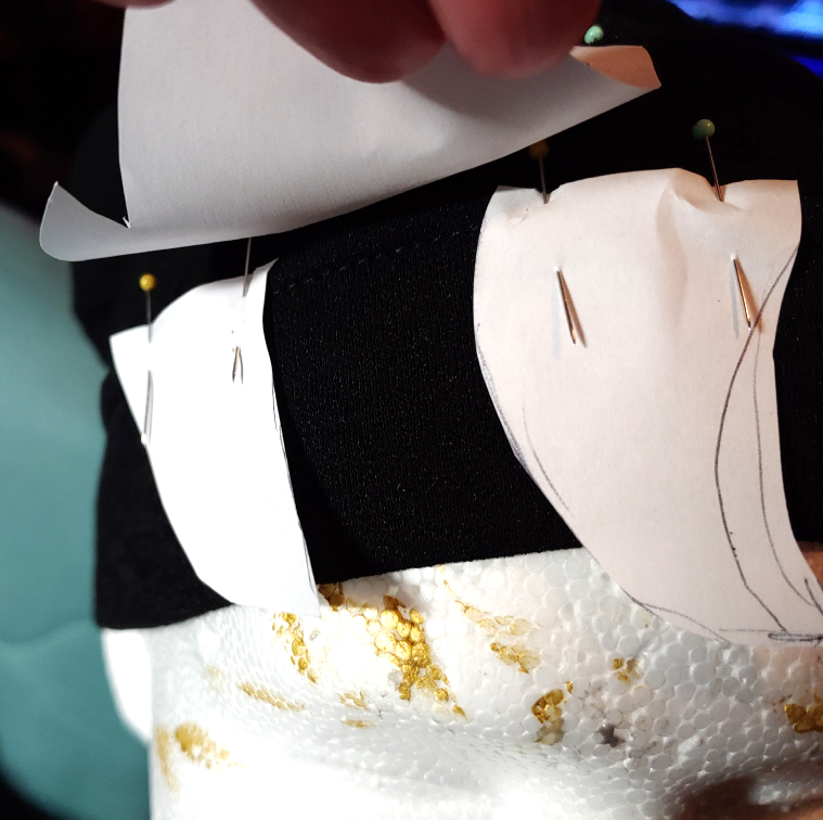 paper lifted up to show two curved bang pieces separated by a gap