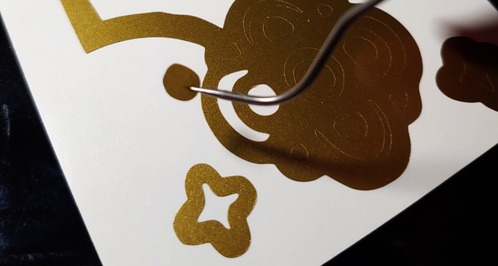 Spearing a tiny circle. Several other pieces of the flower design have already been weeded.