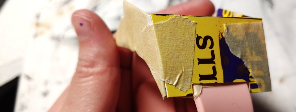 Top-side taped down. The band notch is cut out of the bottom of this side to make room for the watch band