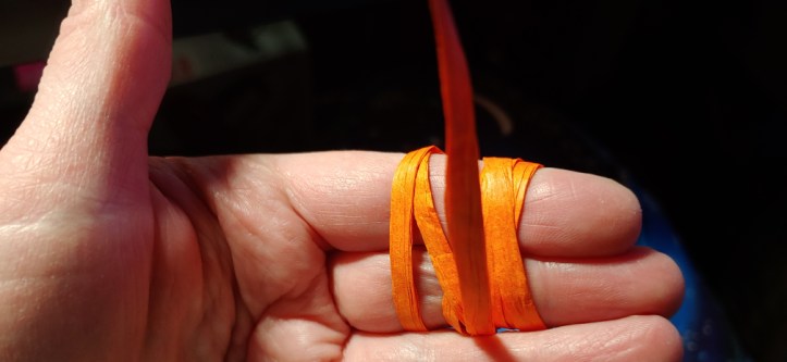 Orange raffia ribbon wound around two fingers to curl it