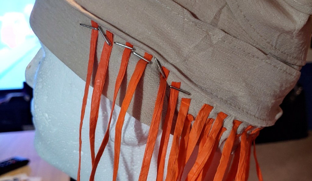 Gluing a few strands over the ear for Row 3. These strands are in orange to match the under layer colors.