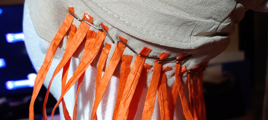 Two rows of raffia ribbon, the strands staggered between them. The top row is glued above the gaps of the previous row.