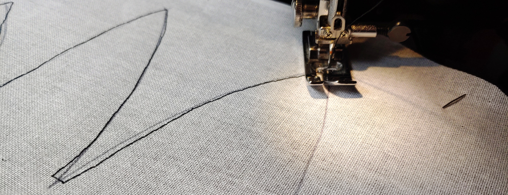 Sewing the feathered outer edge with a sewing machine. The edge is partially finished as the needle and foot follow the pen lines marked on the buckram.