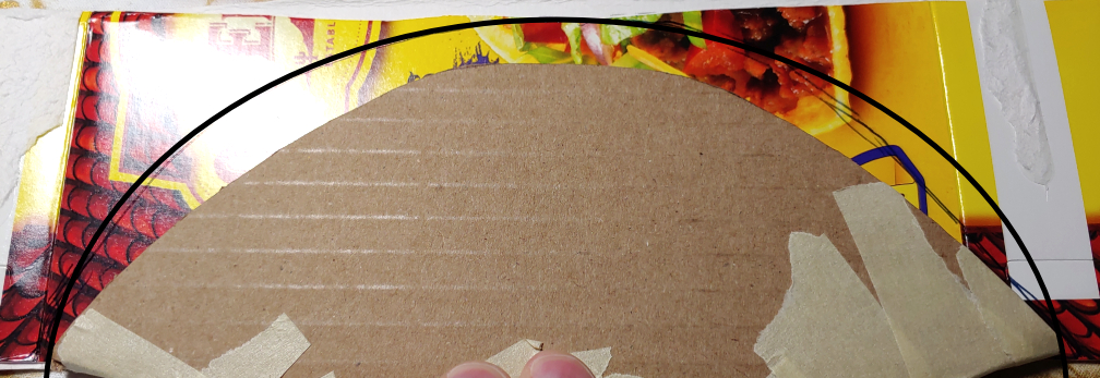 Tracing the shape of the small axe blade on a taco box. Blade shape is traced with a black circle to make it easier to see.