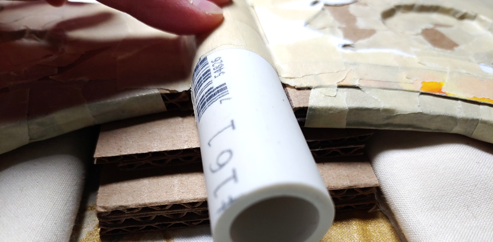 Stabilizing pieces of cardboard placed underneath the axe blade and on top of the main shape at the bottom. The pieces aren't even at the ends.
