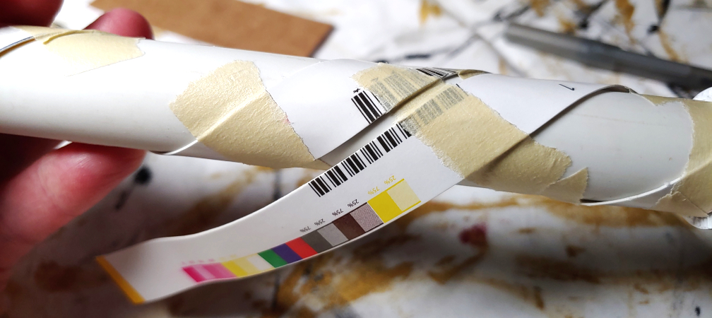 Taping the strips down one at a time in a visible section. Two strips are wrapped and taped while the third is out of view.