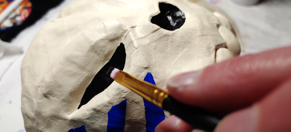 Painting details on a skull using a paintbrush