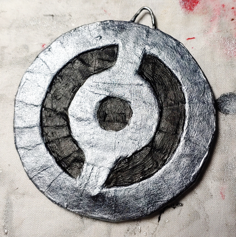Black painted cutouts on a silver medallion