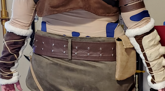 Finished 3" brown studded belt threaded through olive green belt loops with a belt pouch attached.