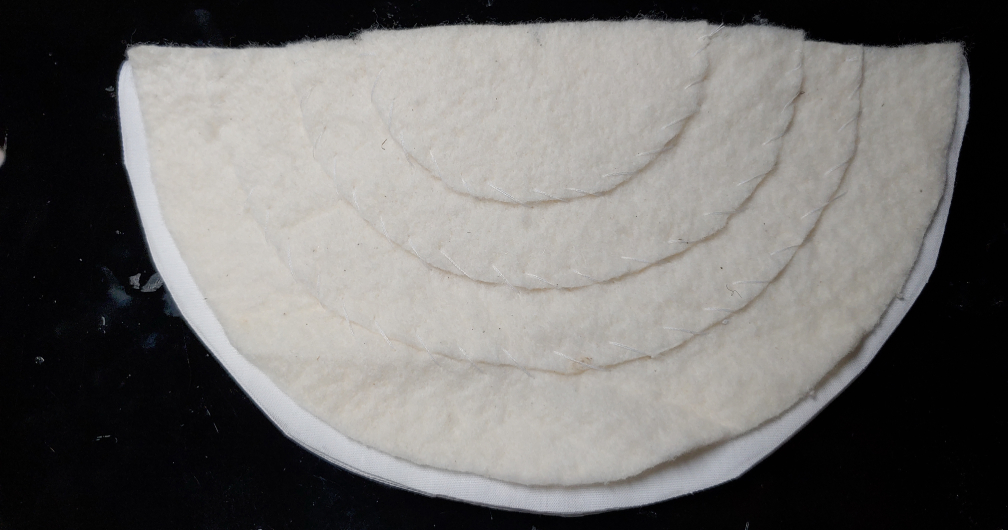 Creating a cover pattern using the shoulder pad itself. Shoulder pad sits on top of white lining fabric folded in half.