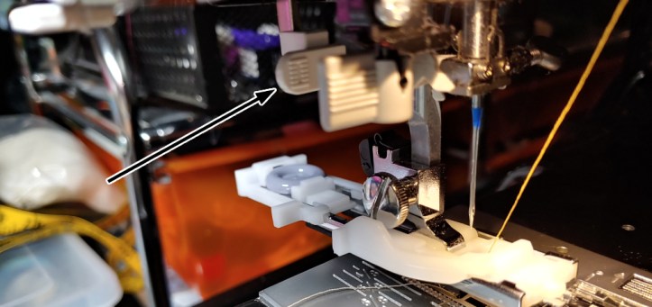 Location of the sensor bar hiding behind the needle threader indicated with a black arrow.