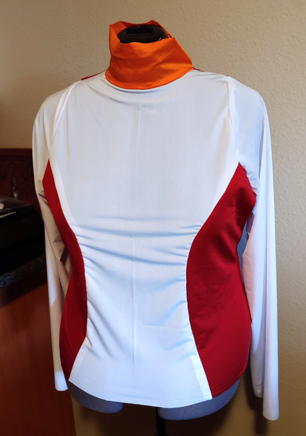 A spandex shirt made of scraps of white, red, and orange sitting on a dress form
