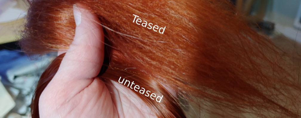 Difference in teased vs unteased fibers for approximately the same amount of fibers. Labeled Teased at the top, the fibers appear lightweight and fluffy. Labeled unteased at the bottom, the fibers appear thinner and shiny