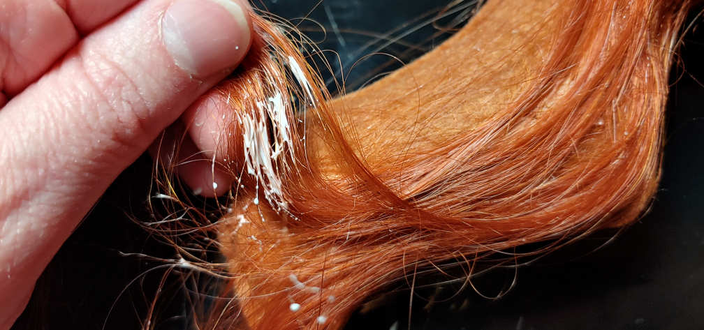 Securing wefts while working around the curves of the pillow. Glue is dabbed on wefts lifted up to show the process before being pressed down on the pillow.