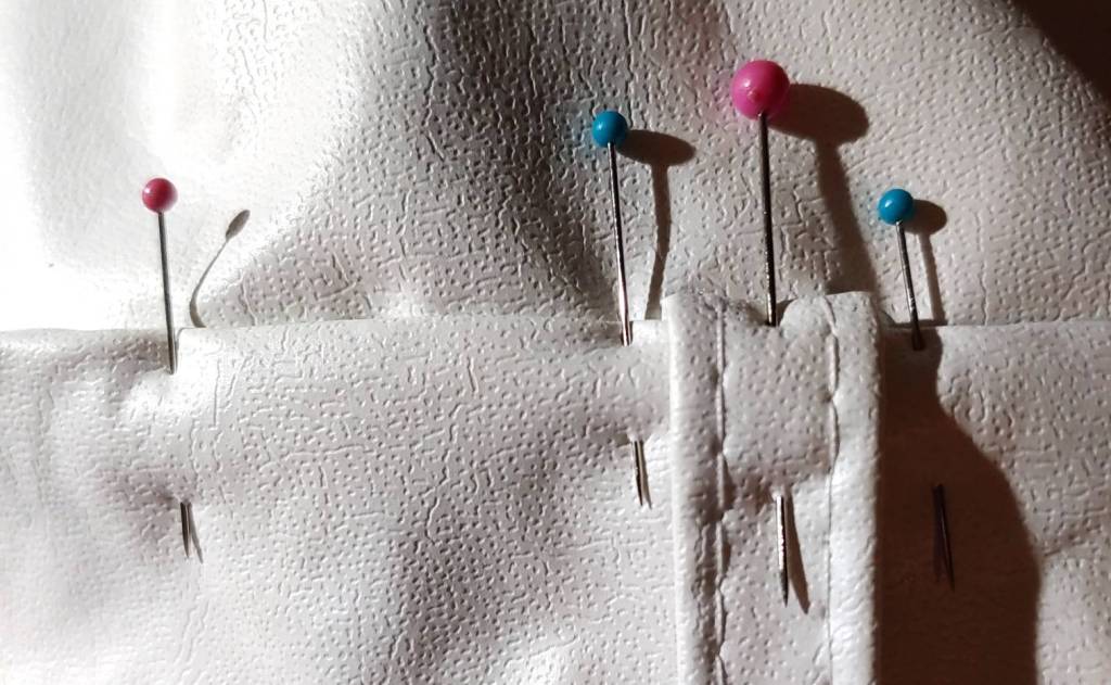 Small and quilting pins used to flatten a seam for topstitching white vinyl.