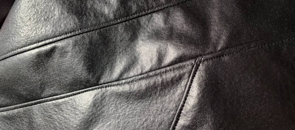 Topstitching on the back of a black tablecloth coat. small stitches sit next to the seams, sewing the fabric flat and making the jacket sit properly when worn.