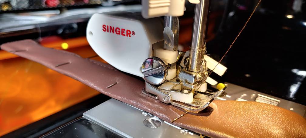 Sewing a belt with a walking foot. A bulbous walking foot is attached to the sewing machine, sewing a brown belt.