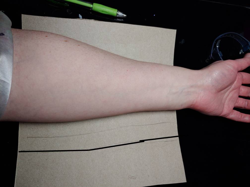 Opened tissue box with half the design traced (emphasized in a thick black line) next to my forearm leaning over my desk