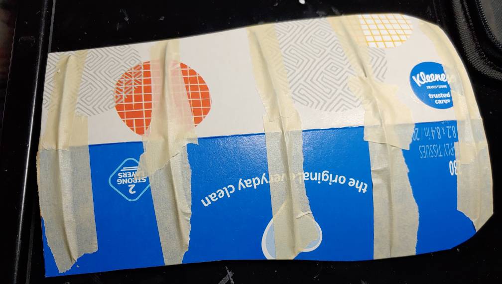 Wire taped down to the tissue box. There are five wires taped down, one at each edge then three in the middle.