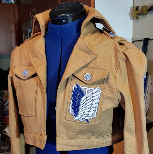Finished beige jacket blue and white patch with pockets sitting on a blue dress form