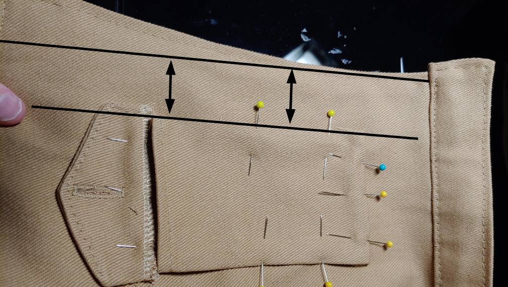 Aligning the pocket with the edge of the fabric. This one has a lapel, so the alignment is a bit strange but still works. Black horizontal lines show the placement of the pocket and the straight edge of the front of the jacket with arrow lines in between them.