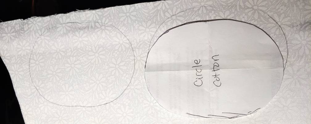 Cutting out the applique fabric. The pattern sits on the right while the circle is traced onto the fabric underneath it and on the left.