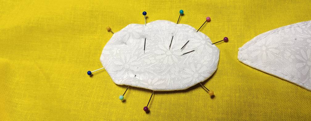 The top pins have been transferred, now pinning the circle to the fabric completely. The bottom pins are still pinned only to the applique fabric and felt.